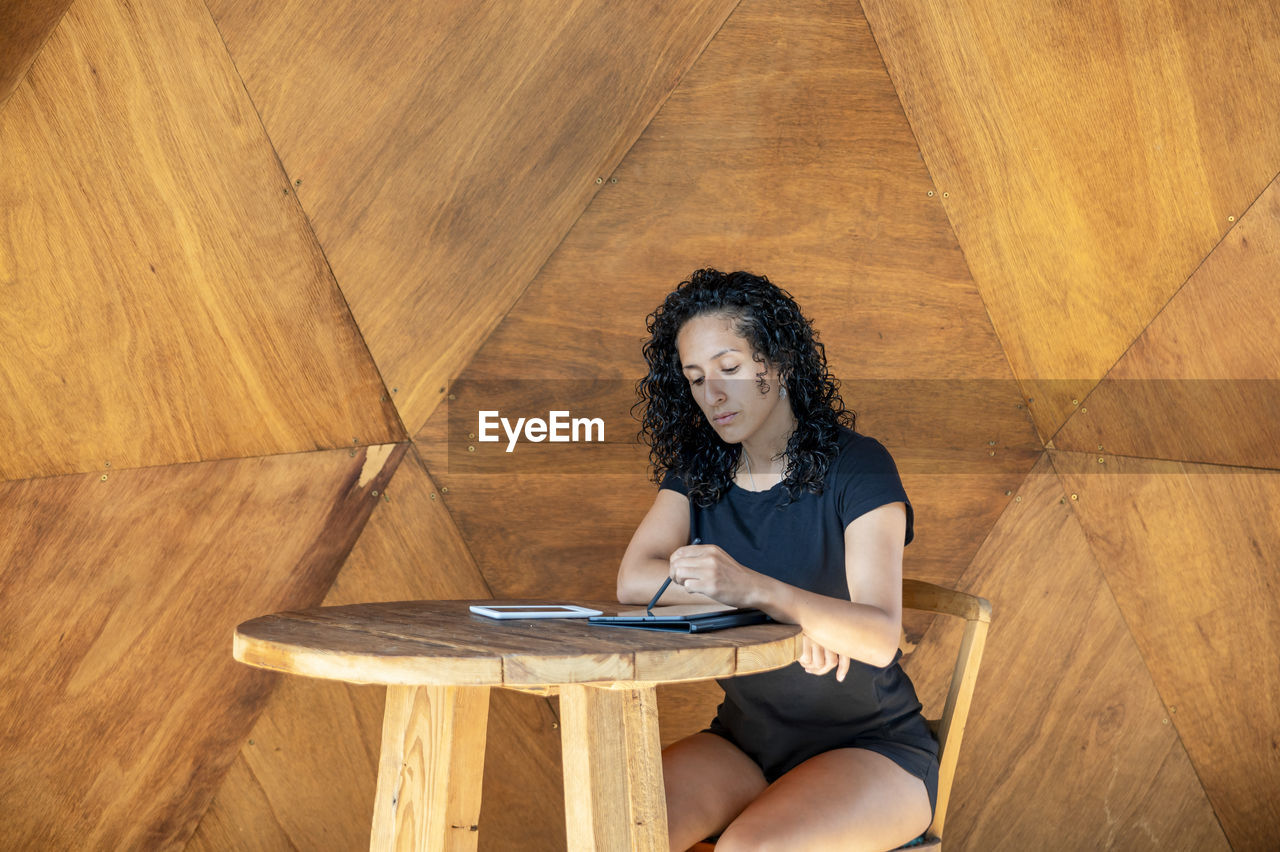 Woman using a digital tablet while sitting at a table.