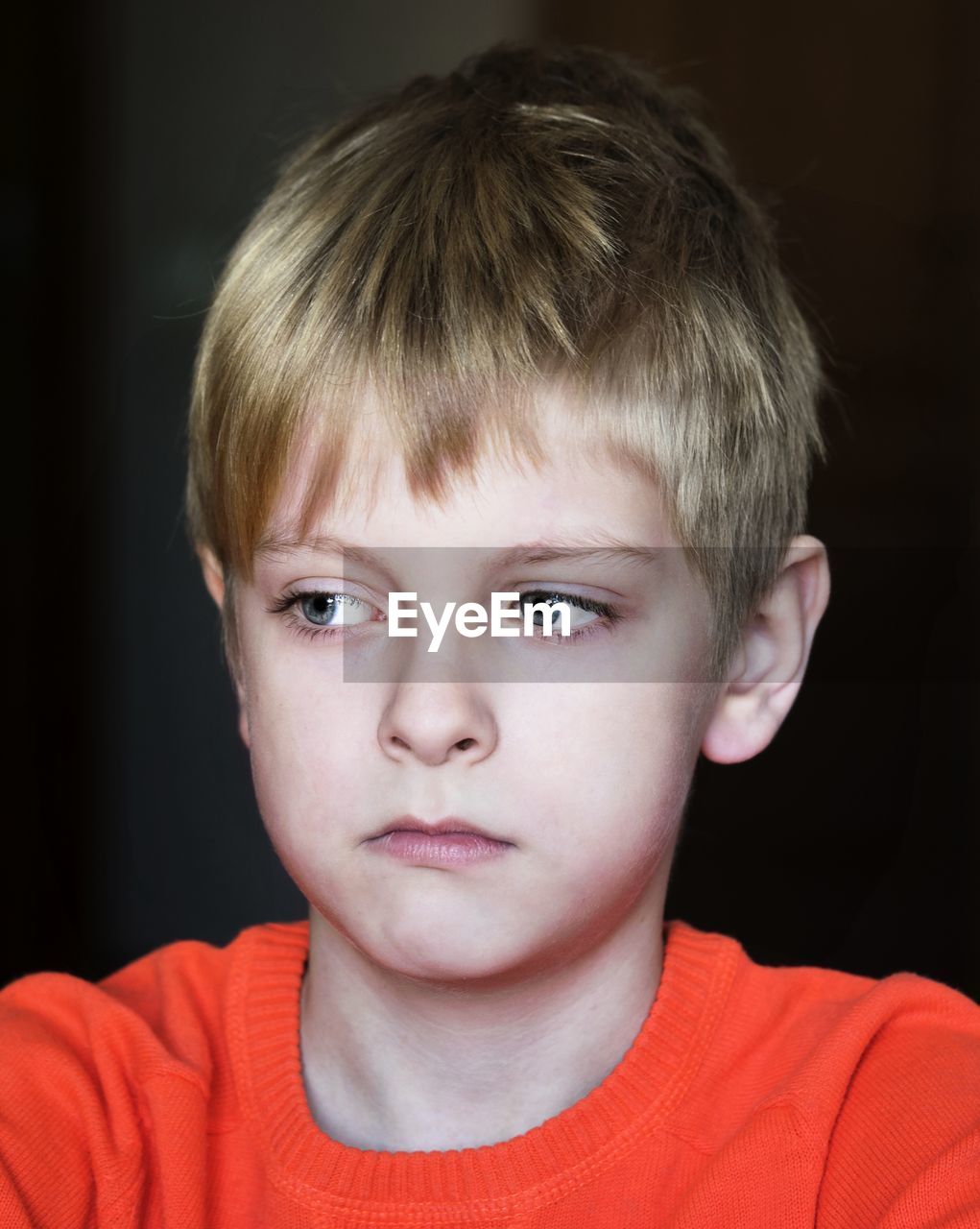 Close-up of sad boy against black background