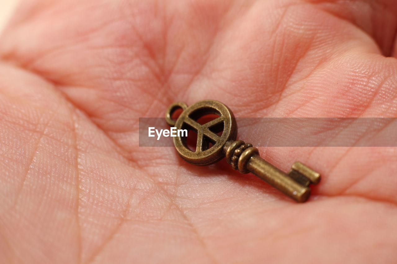 Close-up of human hand holding miniature antique key