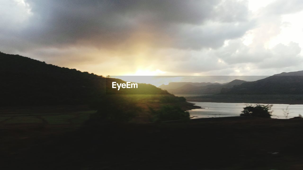 SCENIC VIEW OF MOUNTAINS AGAINST CLOUDY SKY AT DUSK