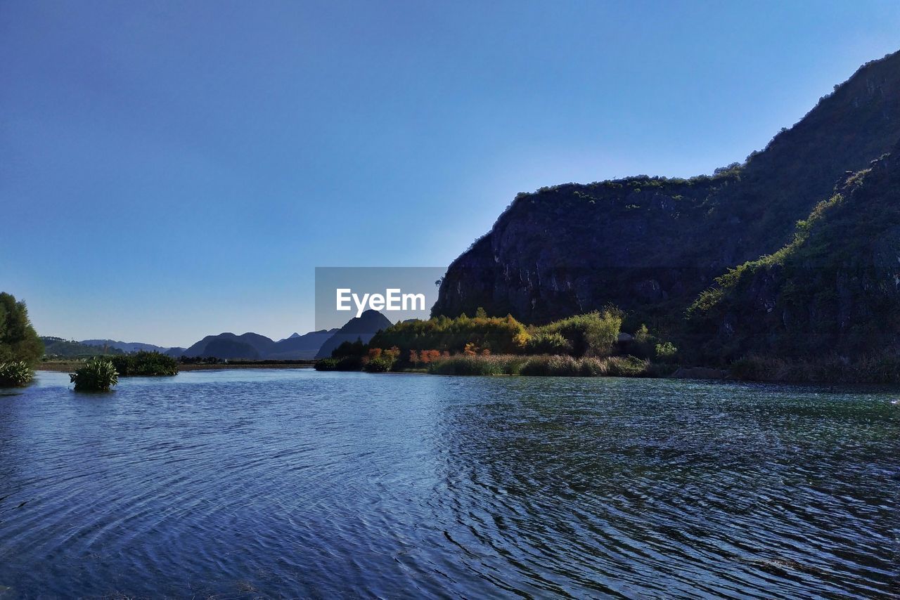 Scenic view of lake against clear blue sky