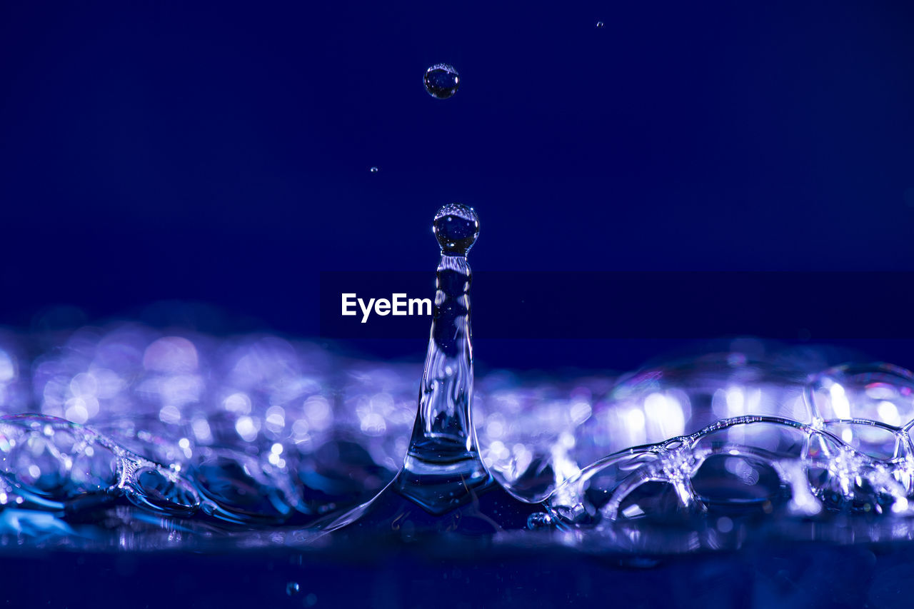 CLOSE-UP OF WATER SPLASHING AGAINST BLUE AND LIGHT