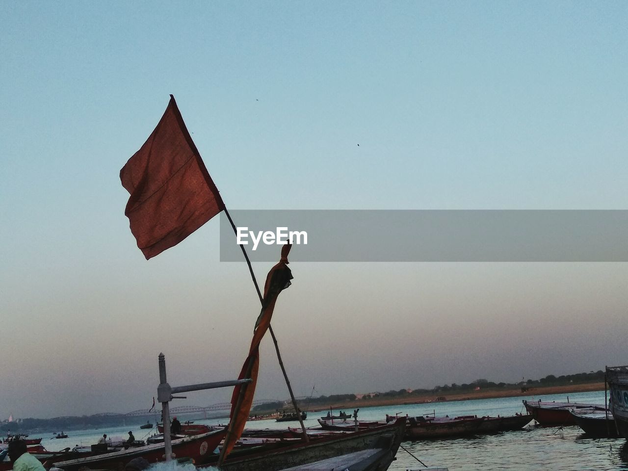 Man sitting in boat against clear sky during sunset