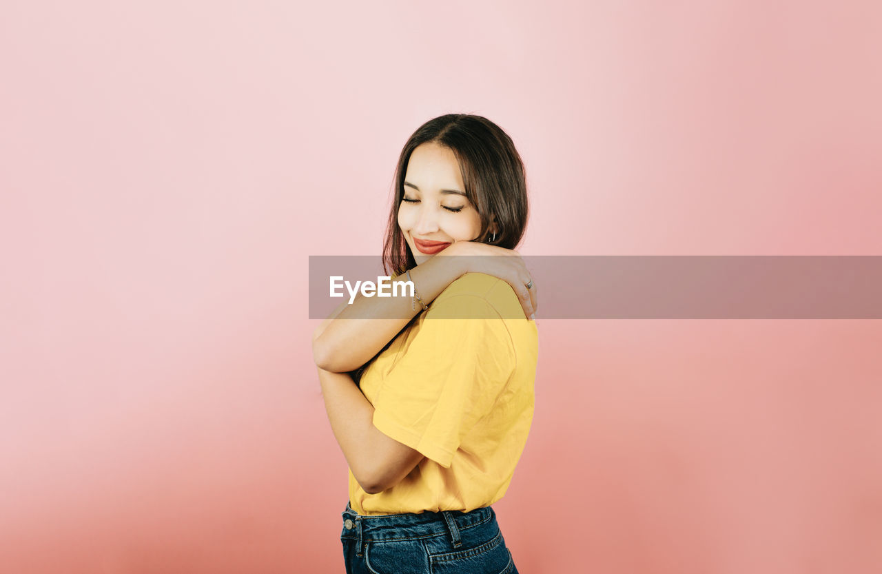 portrait of young woman looking away against pink background