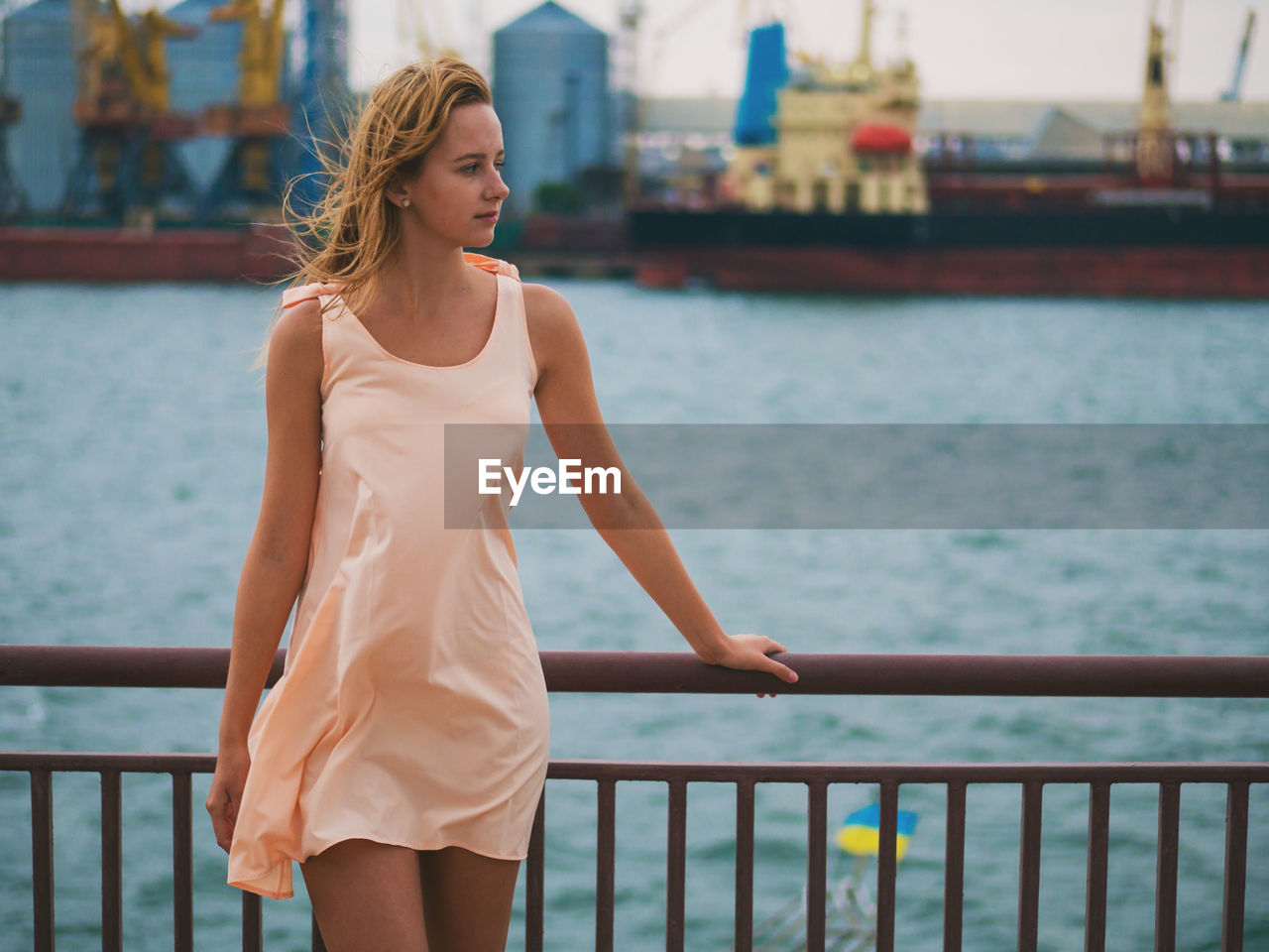 Close-up of young woman standing on railing against sea