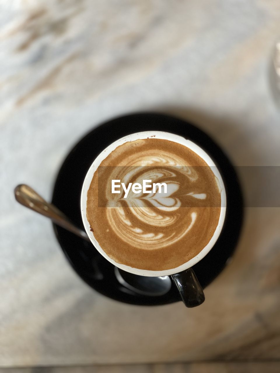 CUP OF COFFEE WITH SPOON ON TABLE