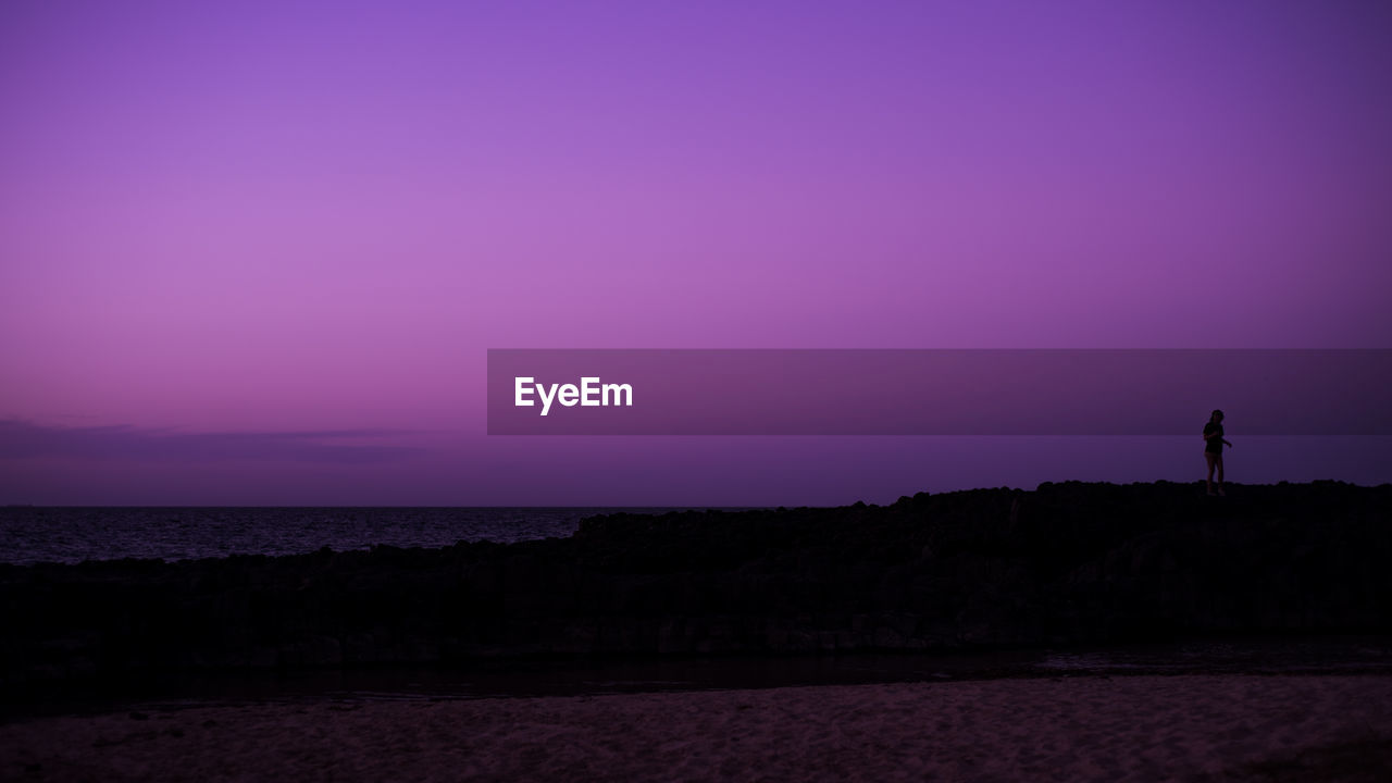 SILHOUETTE OF BEACH AGAINST CLEAR SKY AT SUNSET