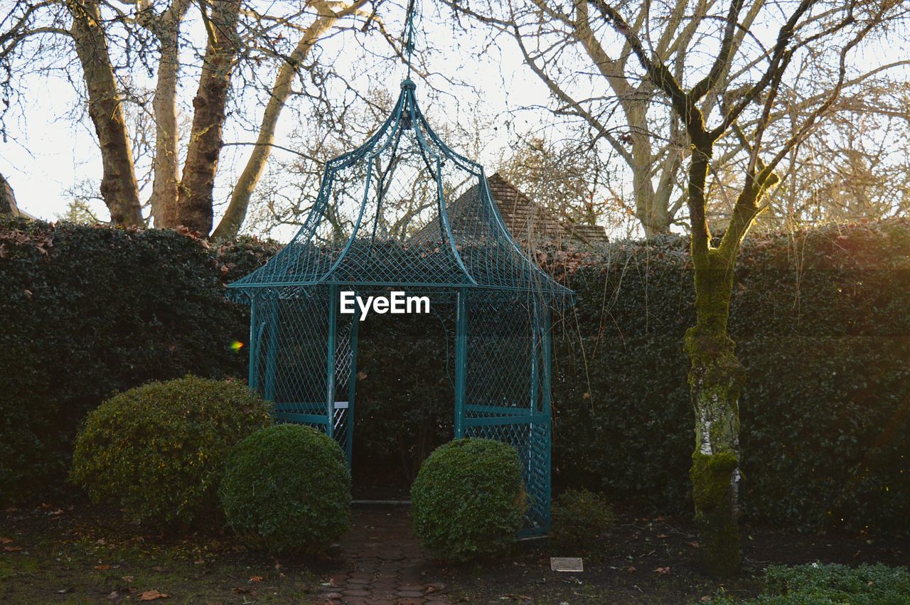 Metallic structure against hedge and trees in park