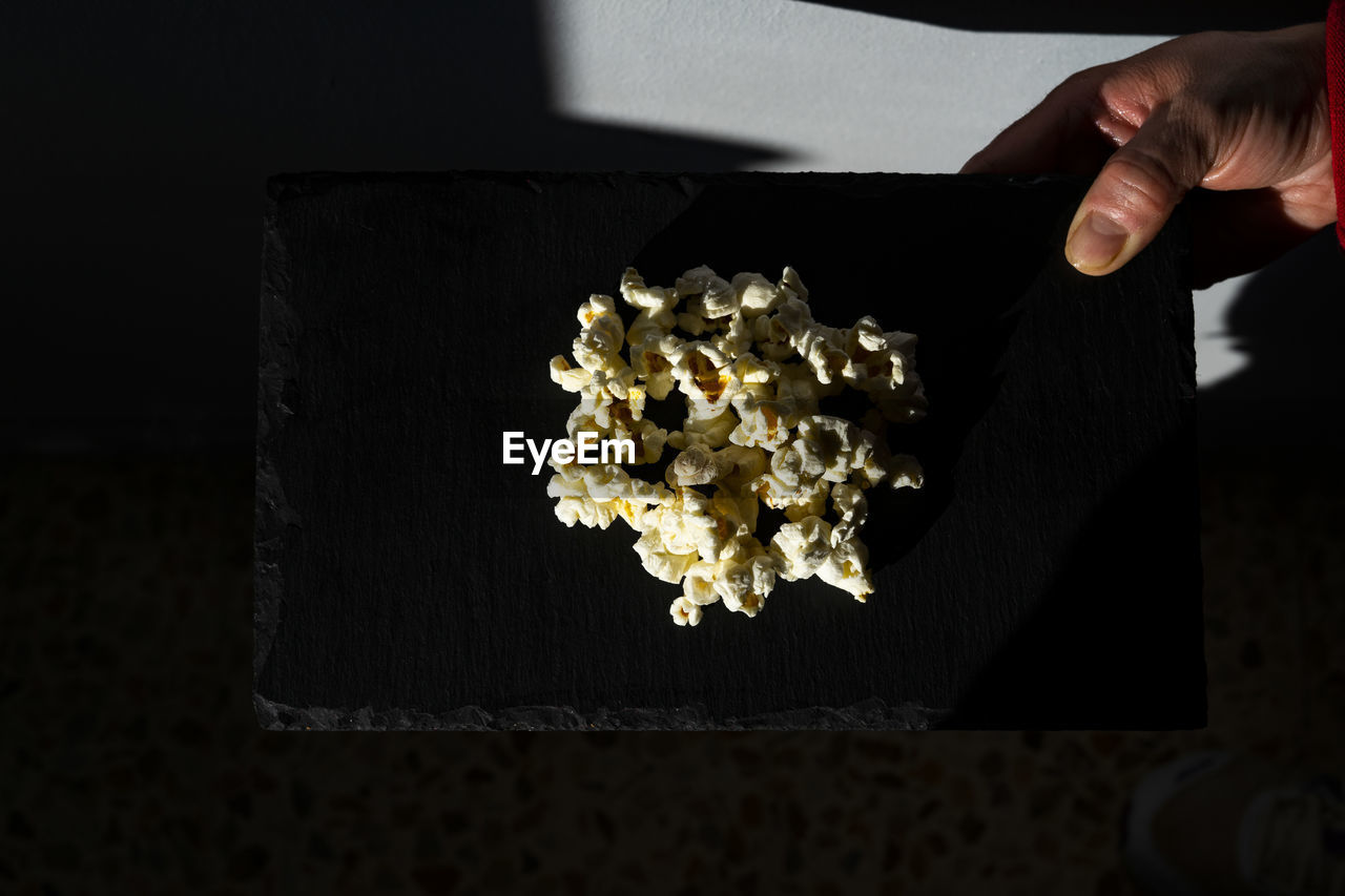 Gourmet popcorn on top of a black plate.