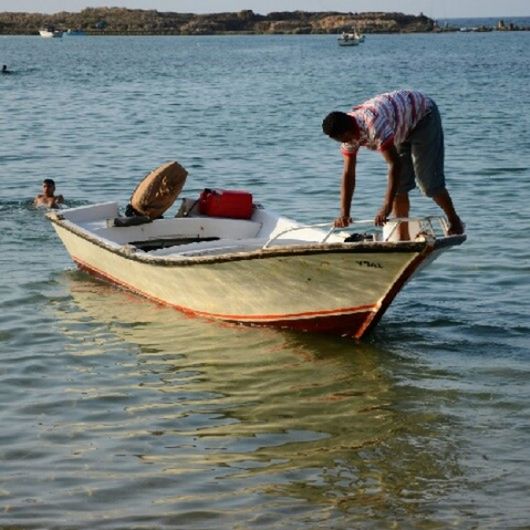 water, nautical vessel, transportation, boat, mode of transportation, sea, boating, vehicle, occupation, men, nature, adult, one person, travel, day, long-tail boat, watercraft, outdoors, fisherman, beach, skiff, sky, shore, fishing, bay, full length, working, standing, casual clothing, waterfront, paddle, land, fishing industry, side view, rippled, oar, three quarter length