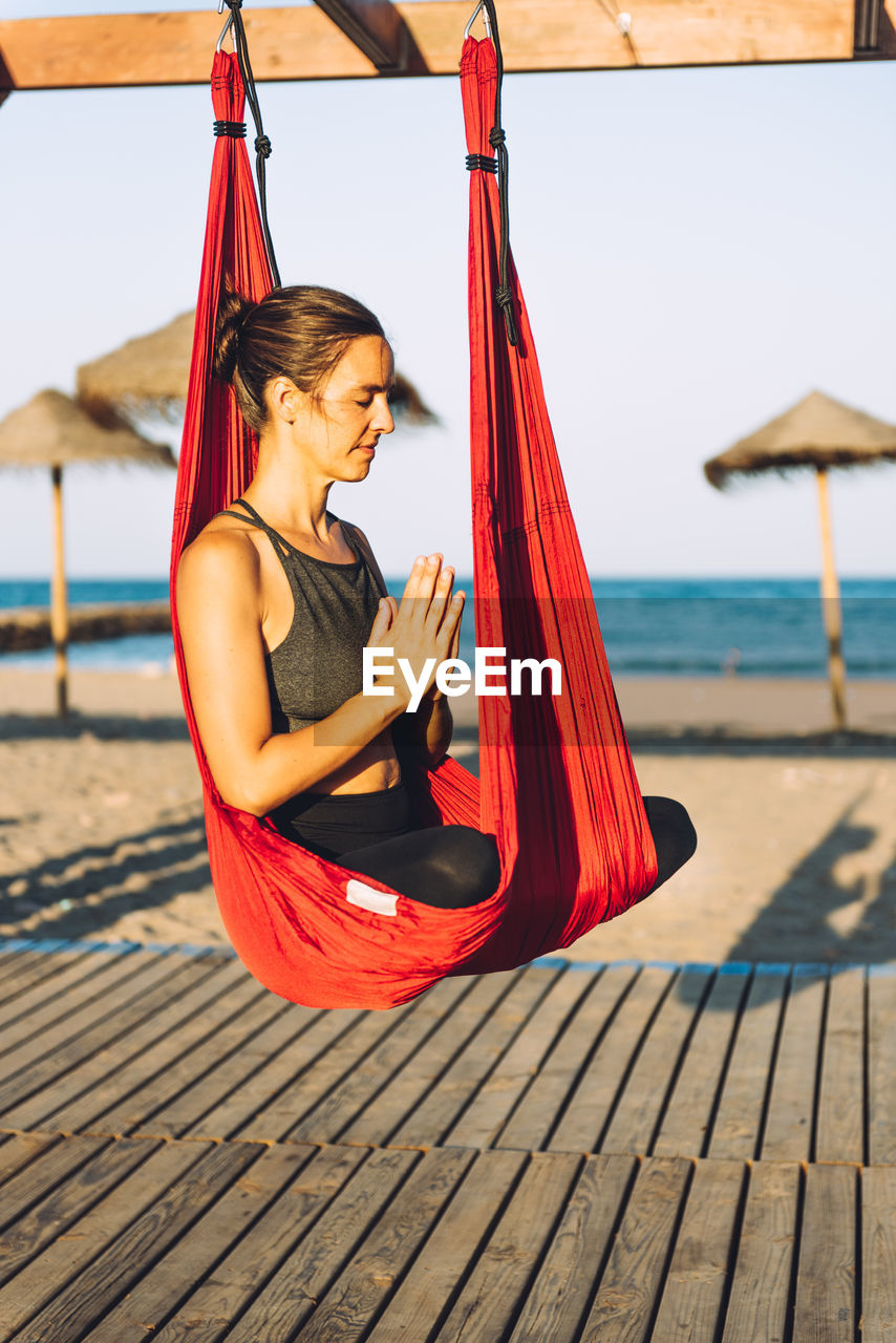 Woman meditating while sitting on silk at beach