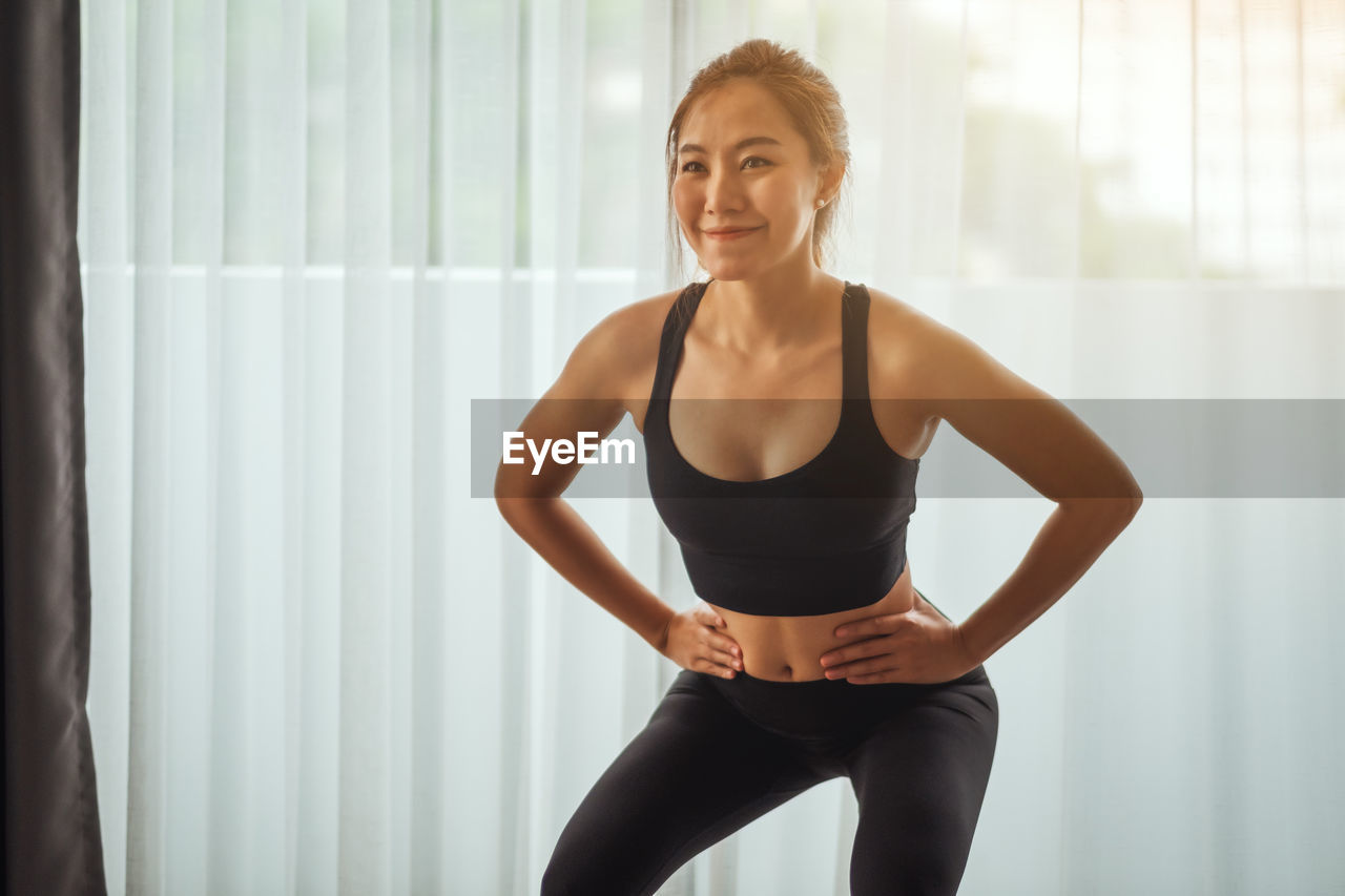 Smiling woman with hand on hip at home