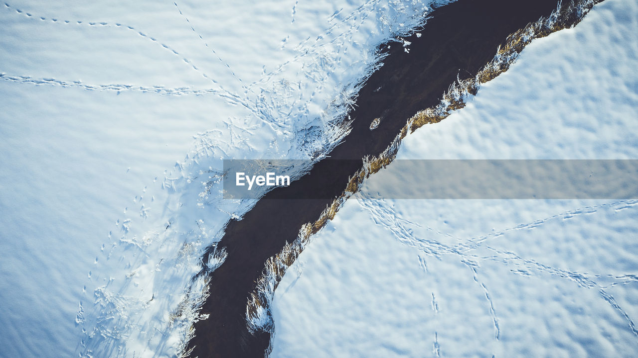 High angle view of river amidst snow covered field