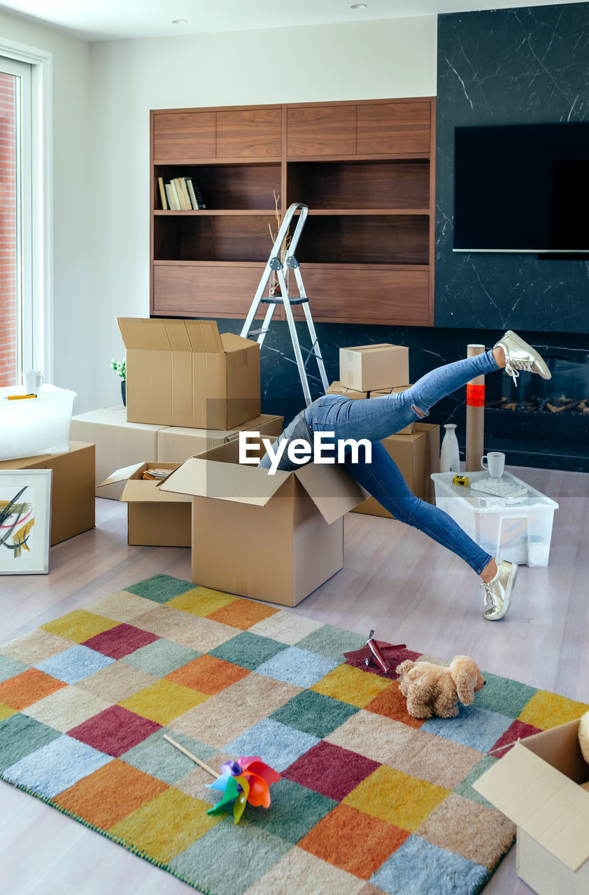 Low section of woman in cardboard box at home