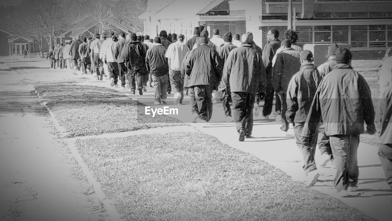 Rear view of prisoners walking on walkway