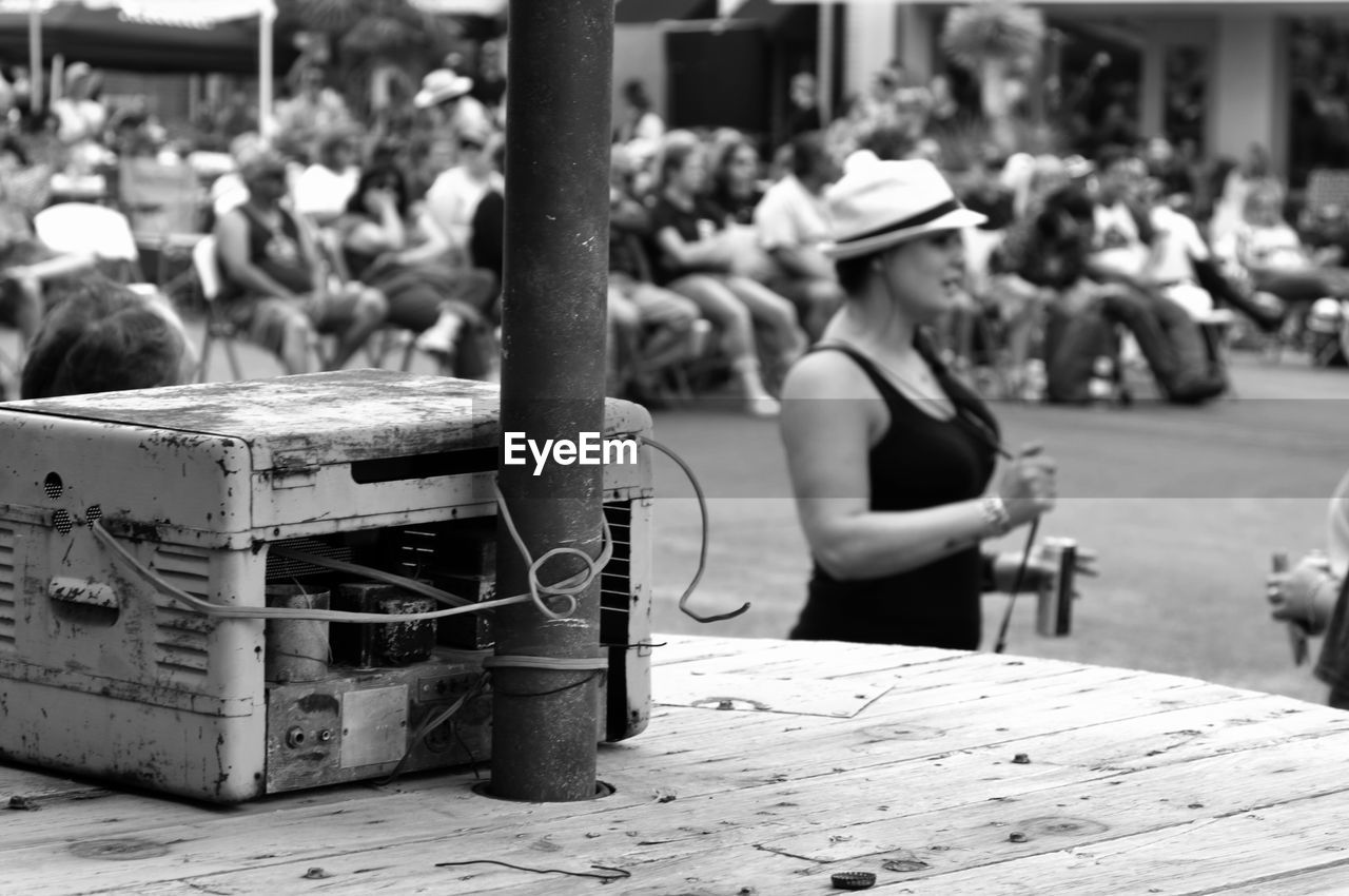 Rusty machine part by pole on table against people at footpath