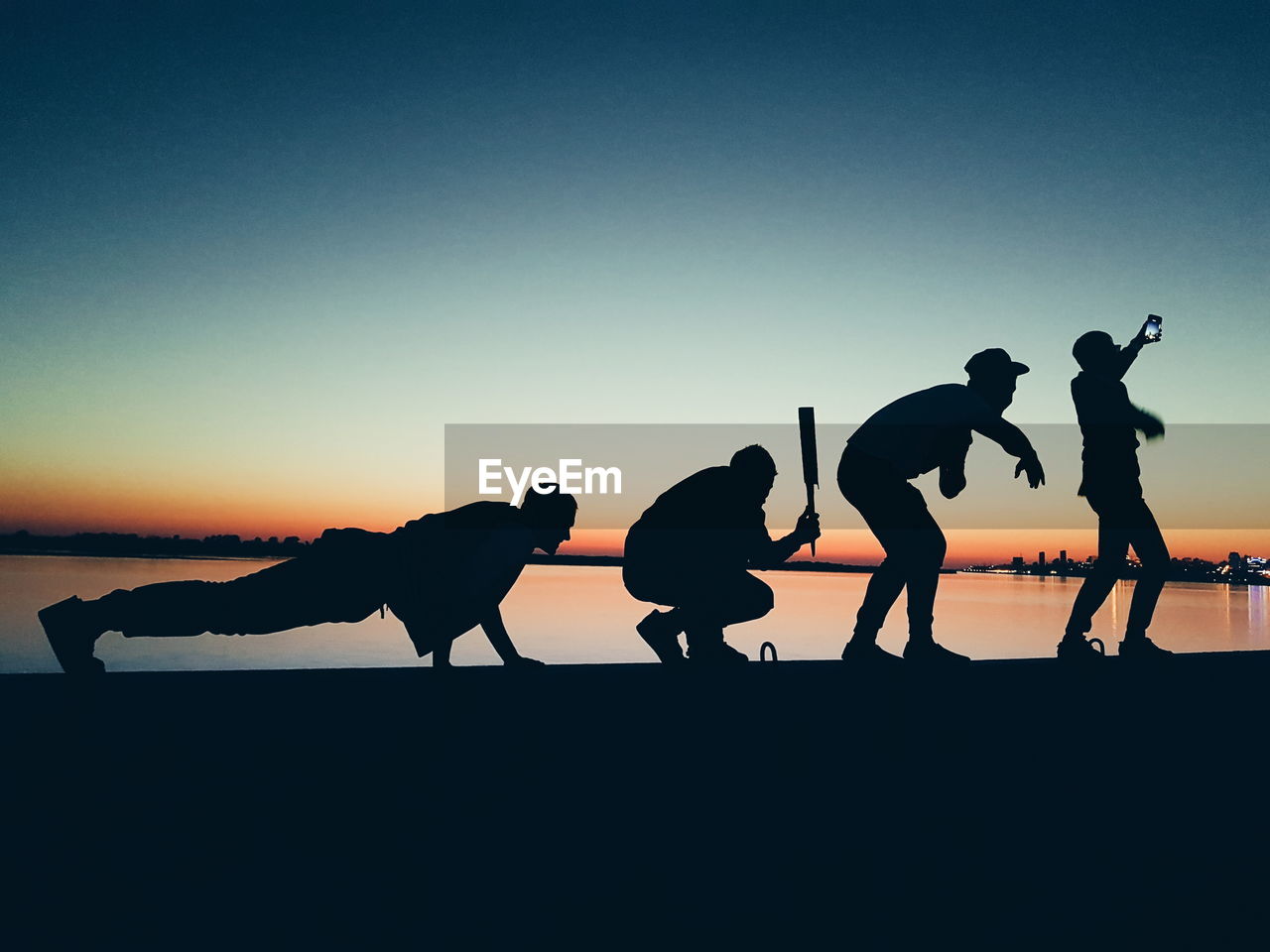 Silhouette people on beach against clear sky during sunset