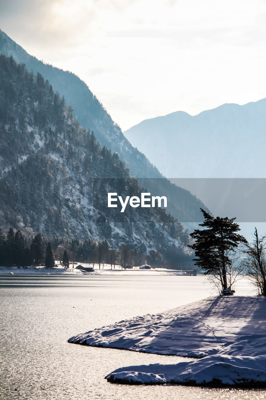 Scenic view of lake by mountains against sky