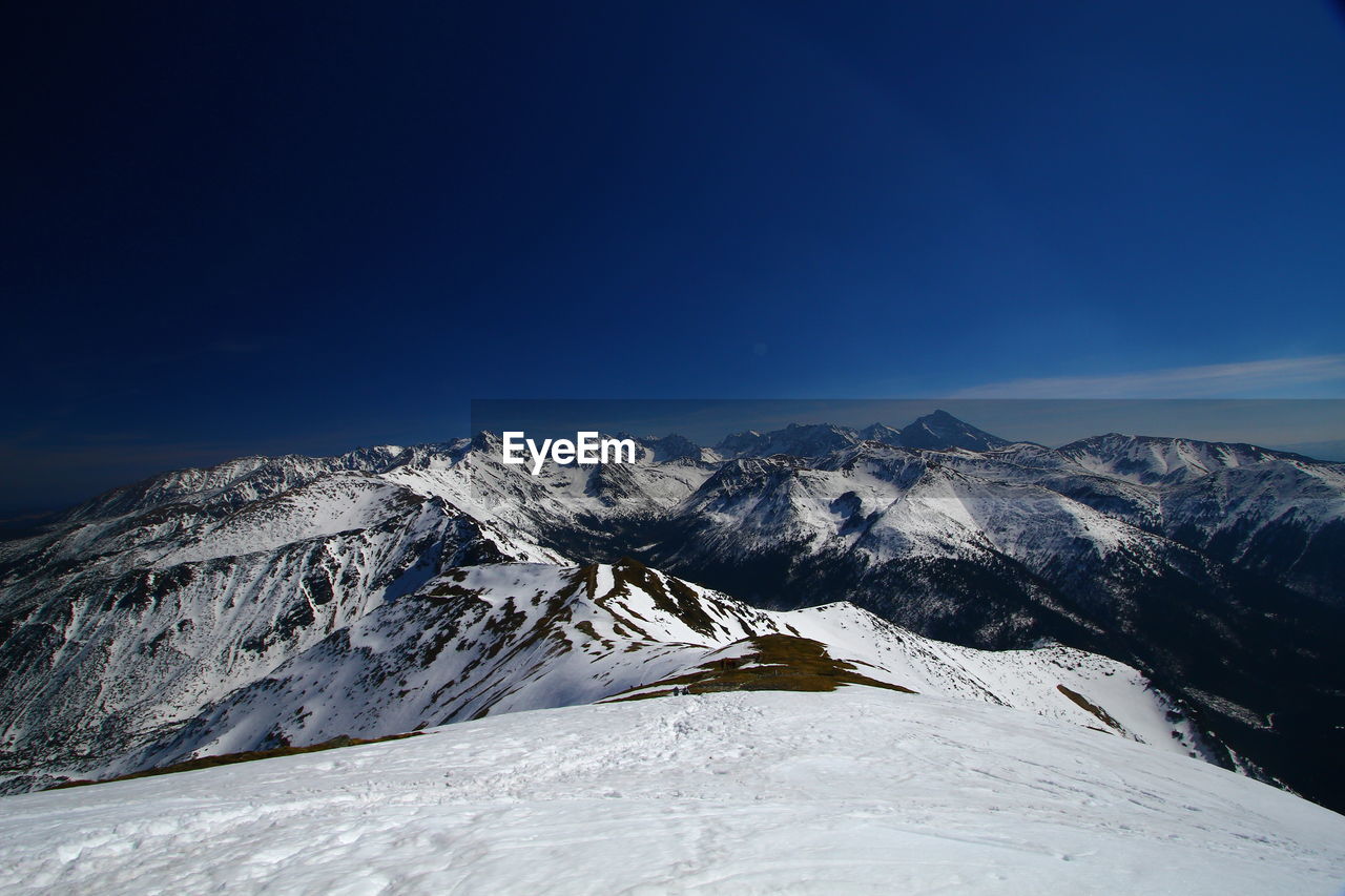 Scenic view of snowcapped mountains against blue sky