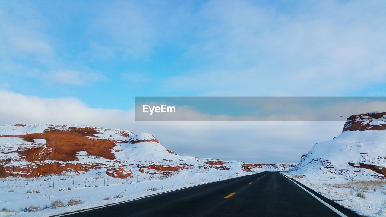 Empty road along snow covered landscape