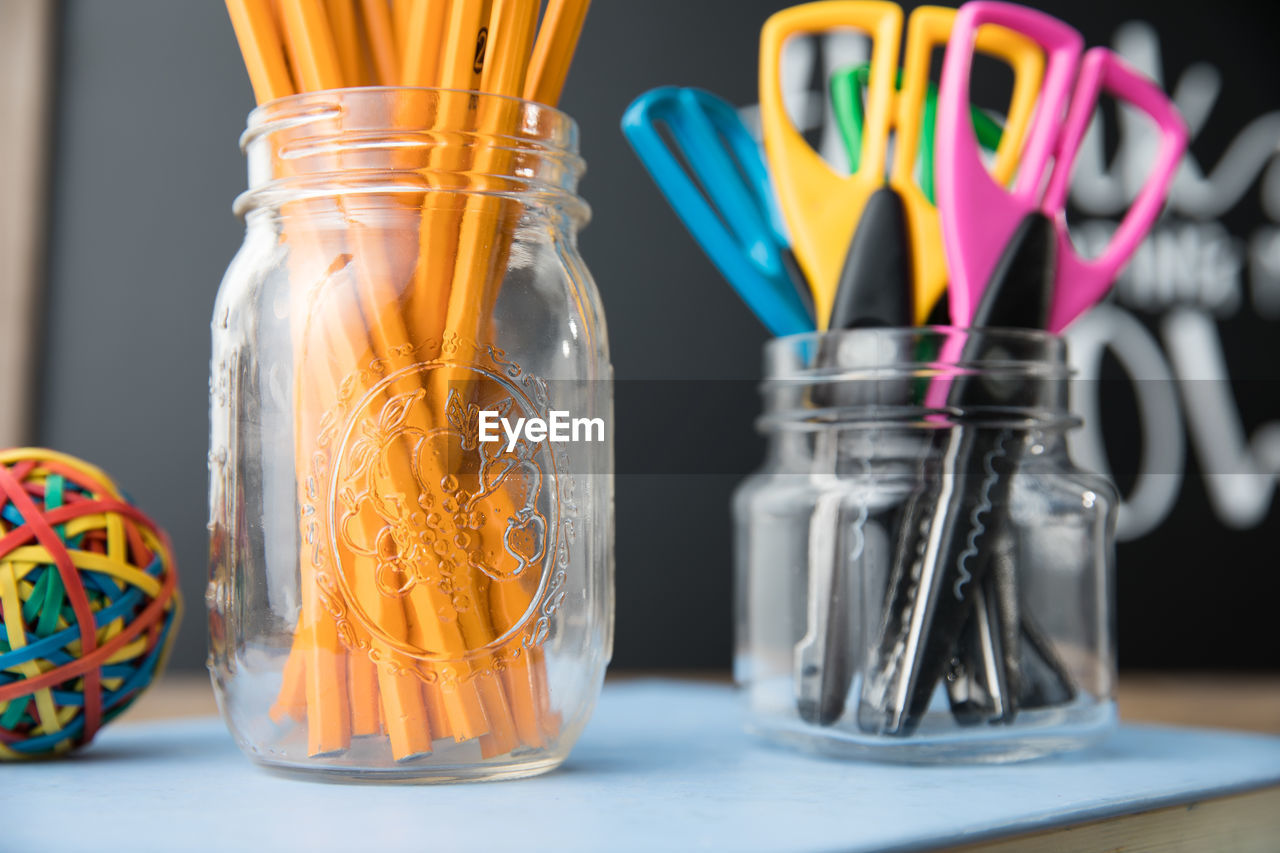 Close-up of classroom supplies on desk with chalkboard background