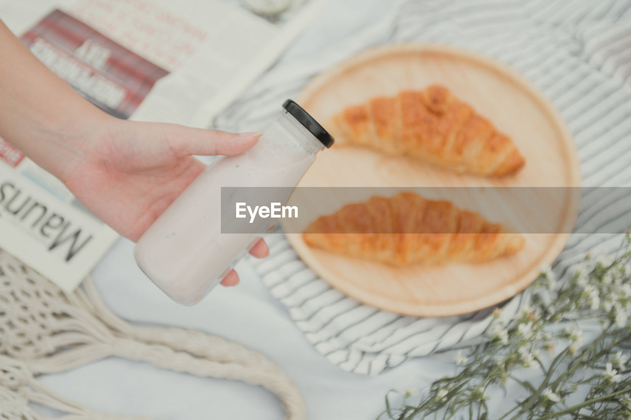 hand, one person, food and drink, food, adult, indoors, women, lifestyles, baked, fast food, holding, paper, close-up, high angle view, wellbeing, domestic room, bread