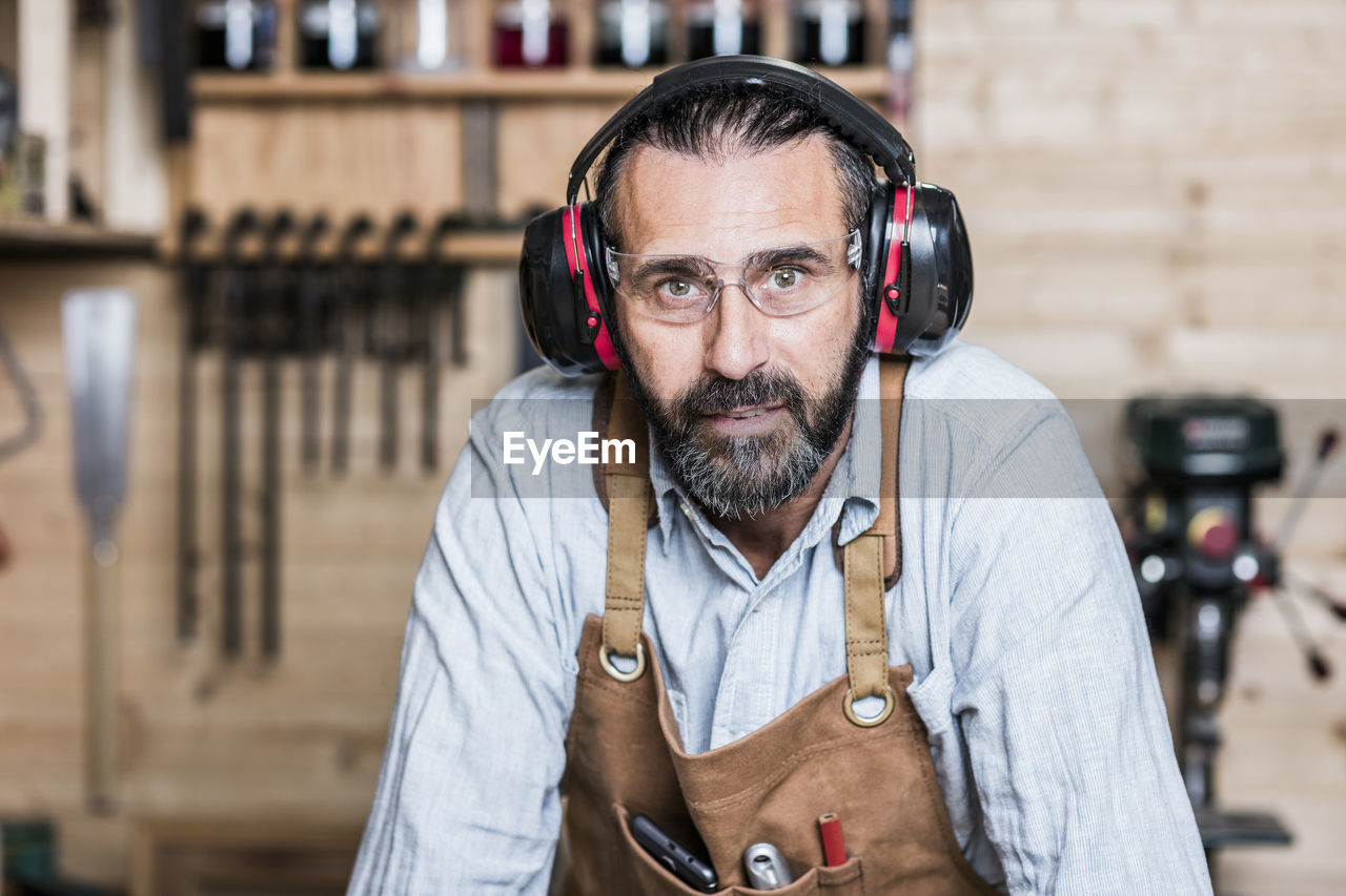 Portrait of carpenter listening music in workshop