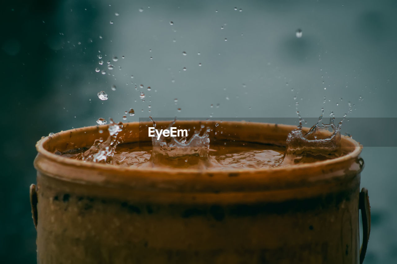 Rain water drop falling to the pail in heavy rain day