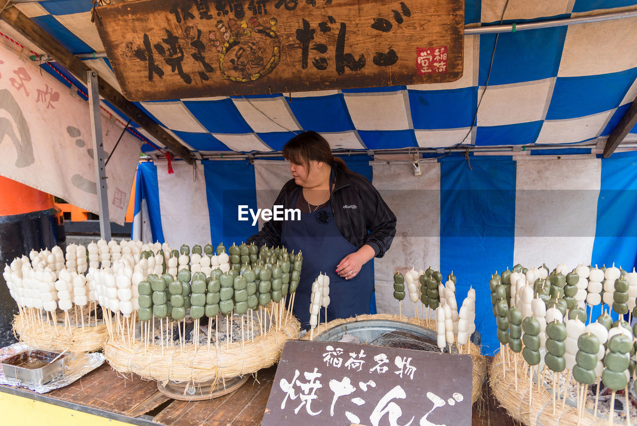 WOMAN STANDING AT MARKET STALL