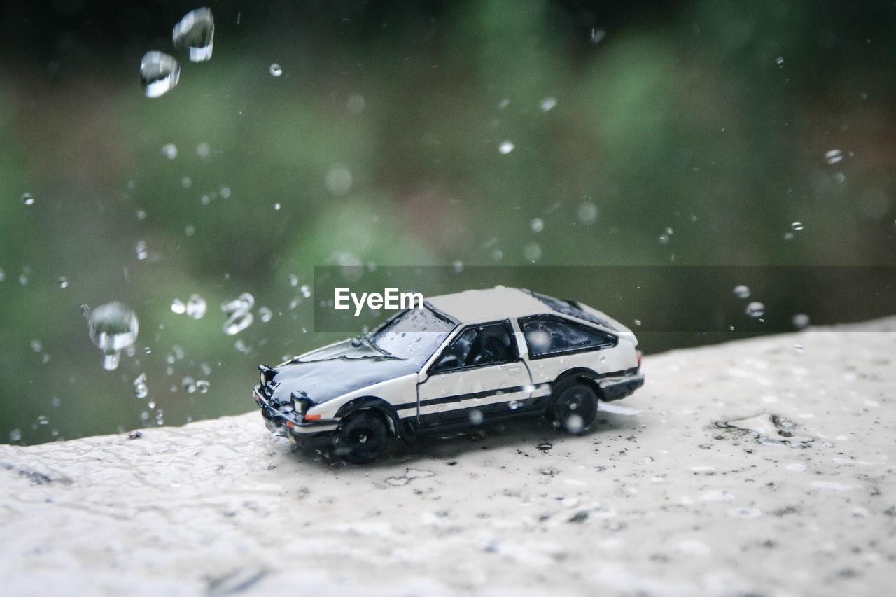 Close-up of toy car on retaining wall during rainy season