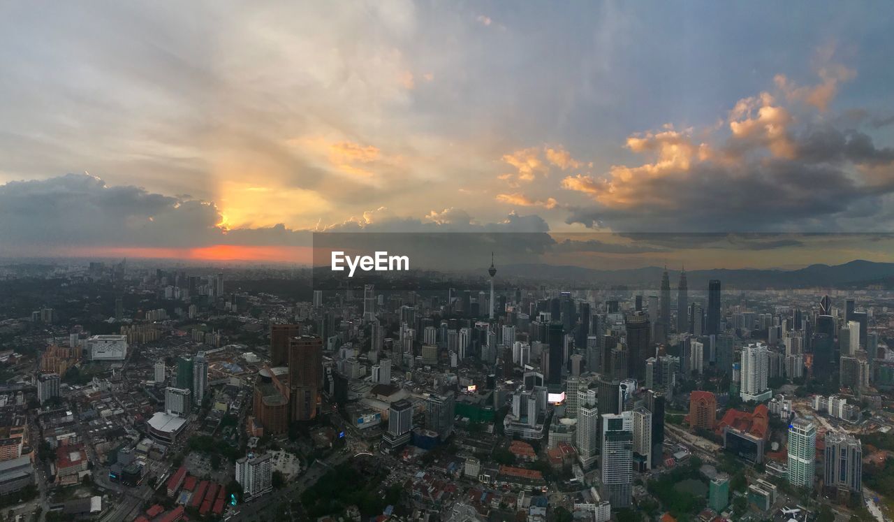 Aerial view of cityscape against cloudy sky