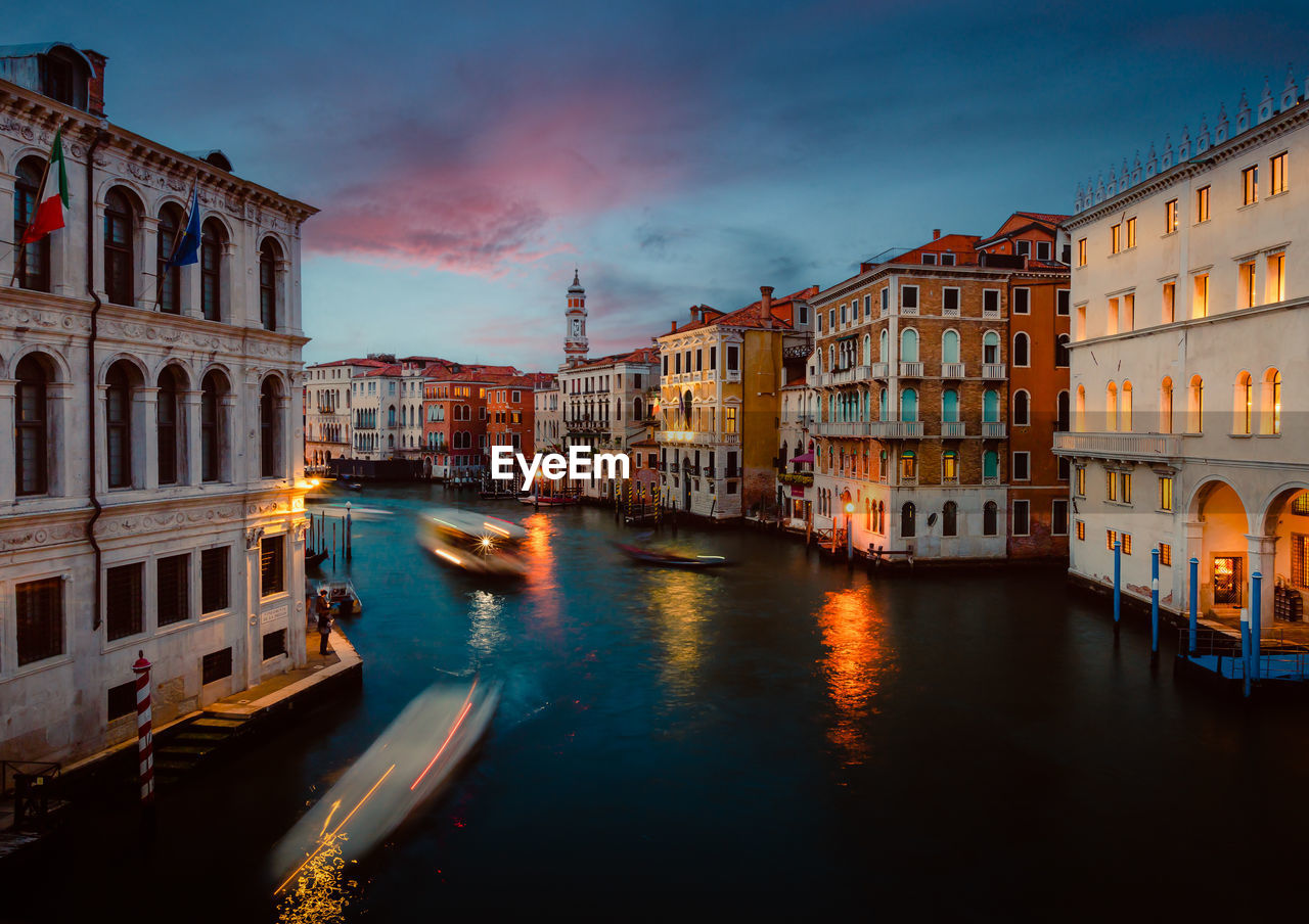 Venice grand canal at sunset with boat trails and illuminated historic buildings, long exposure