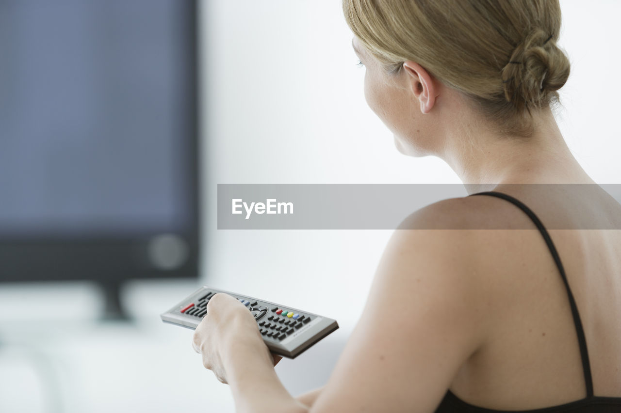 Close-up of woman changing tv channel at home