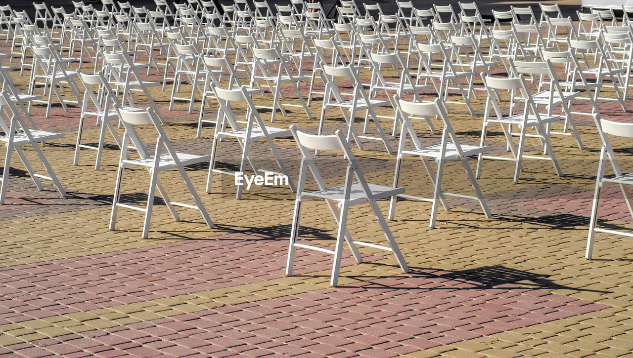 Folding white chairs are placed on the square in anticipation of concert, performance.