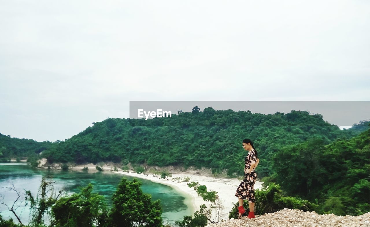 Woman standing at beach against sky