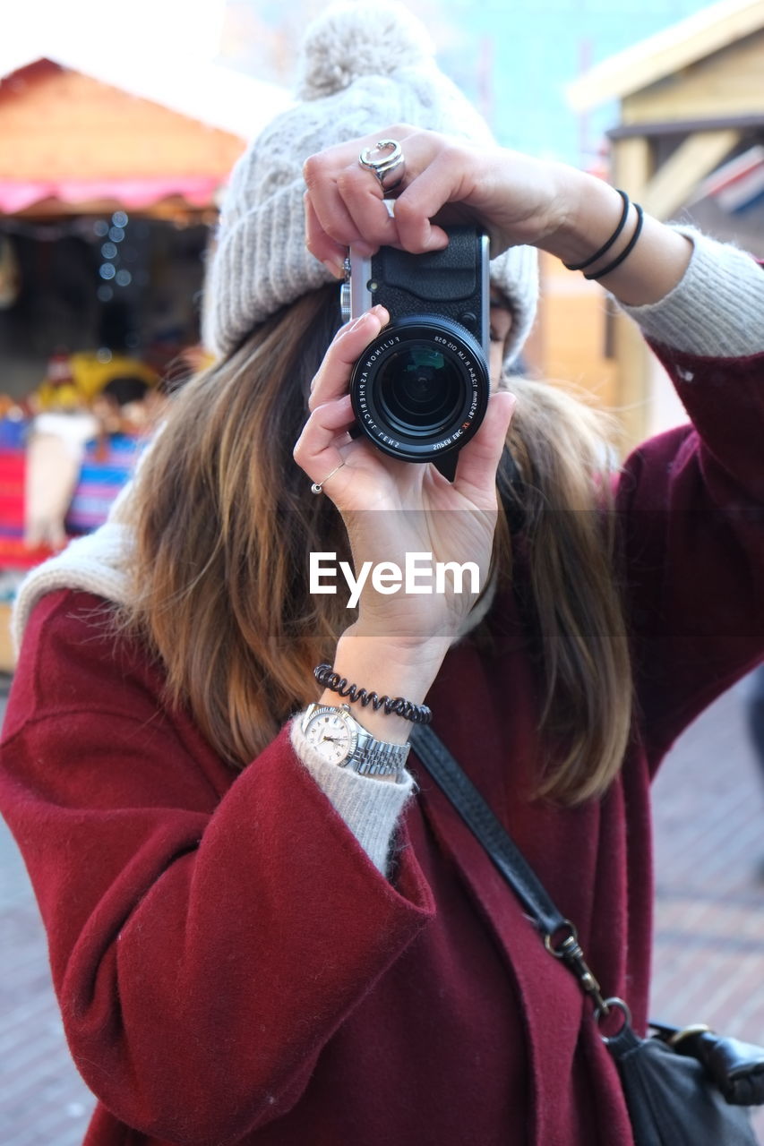 Young woman photographing through camera in city