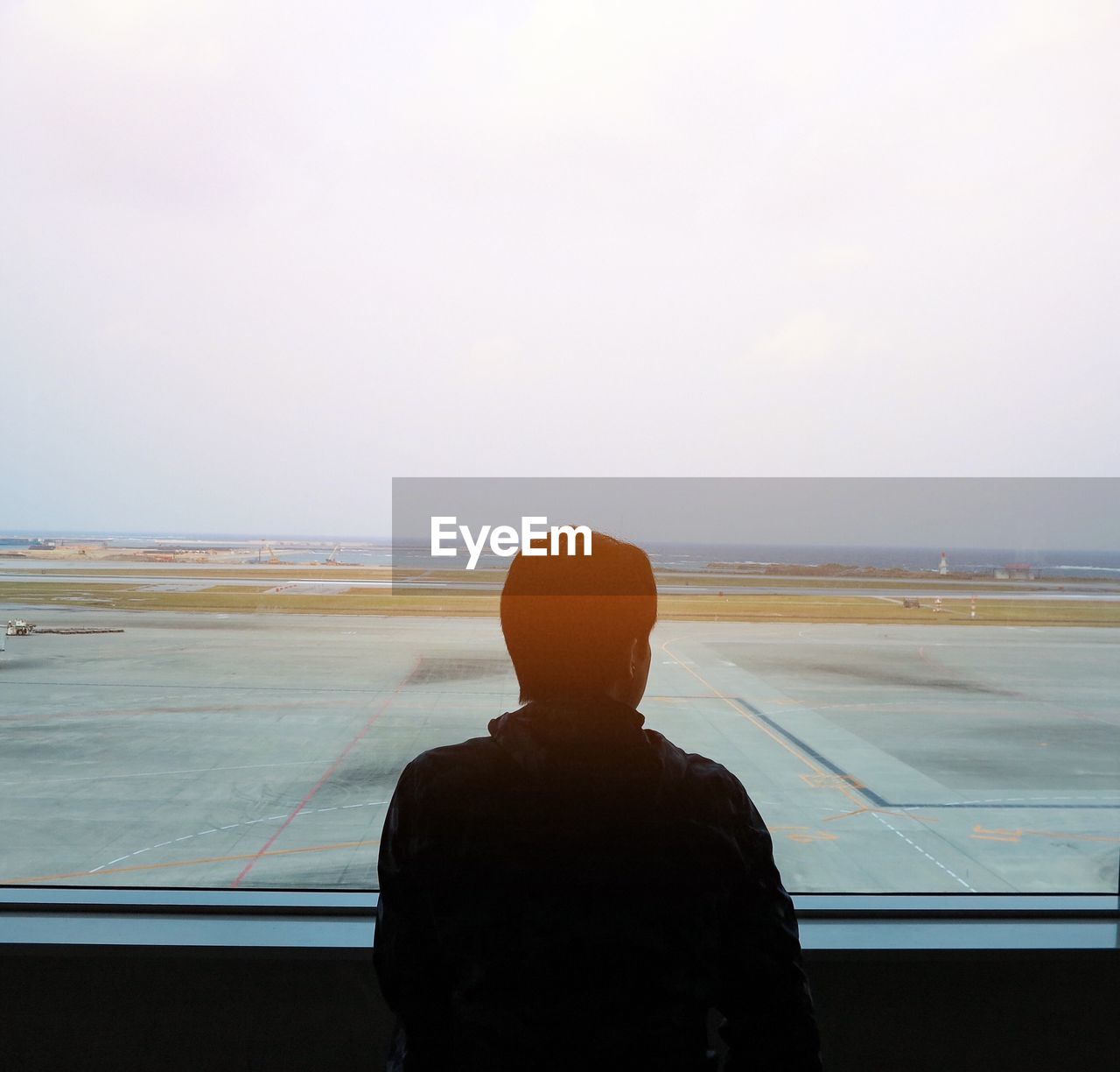 REAR VIEW OF MAN LOOKING AT SEA AGAINST SKY