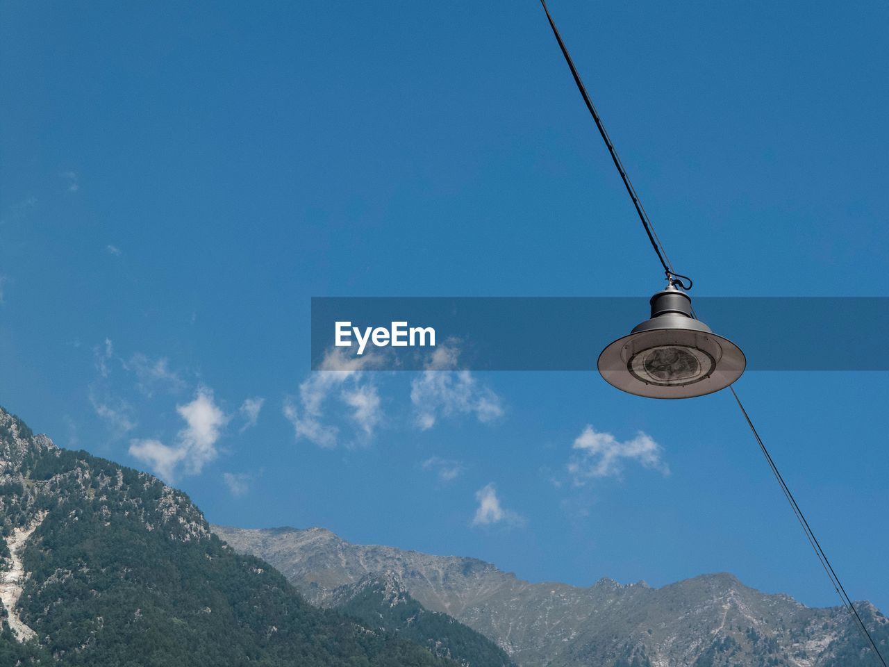 LOW ANGLE VIEW OF OVERHEAD CABLE CARS AGAINST MOUNTAINS