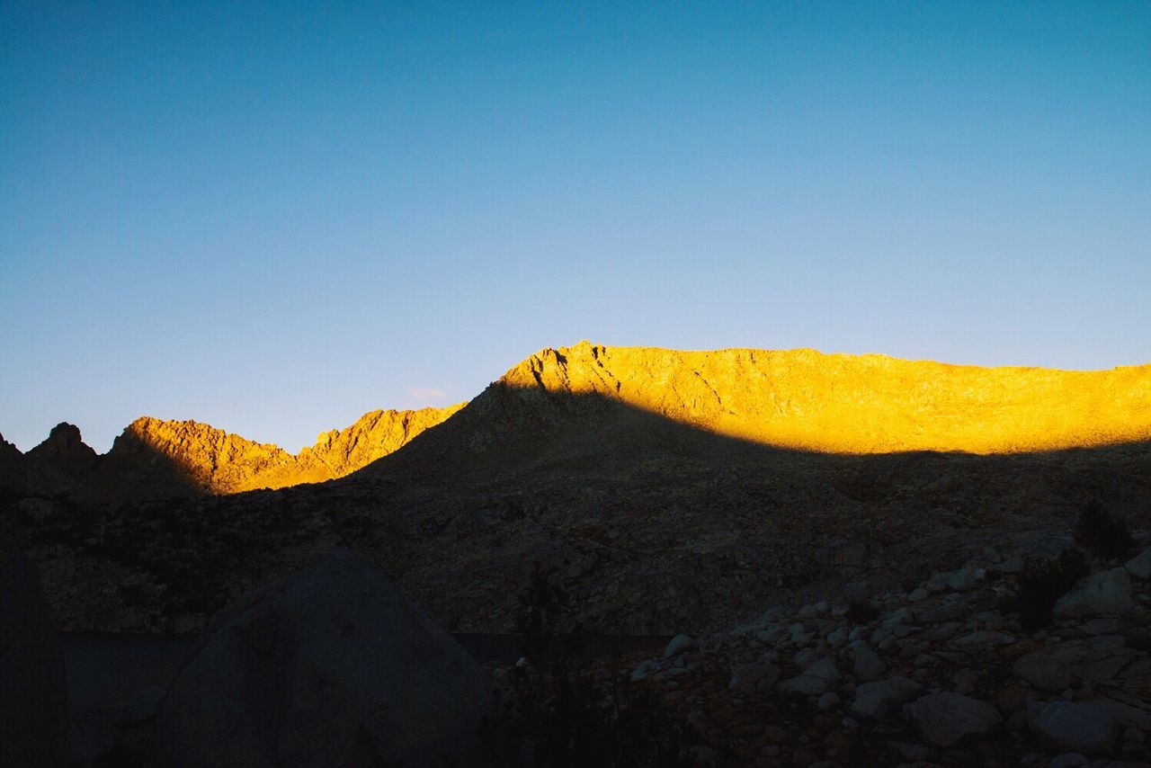 Low angle view of mountain against clear blue sky during sunset