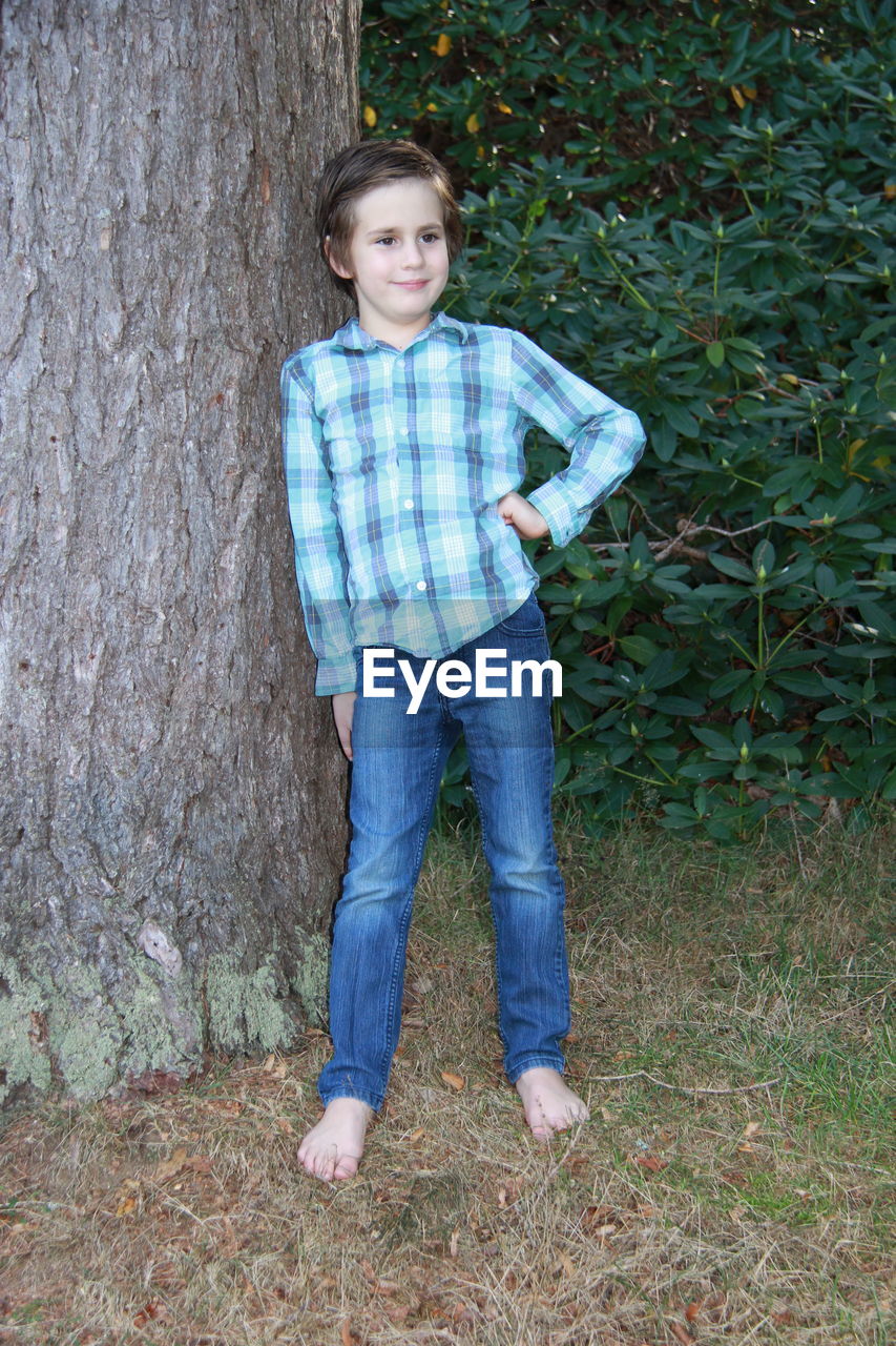 PORTRAIT OF SMILING GIRL STANDING ON TREE