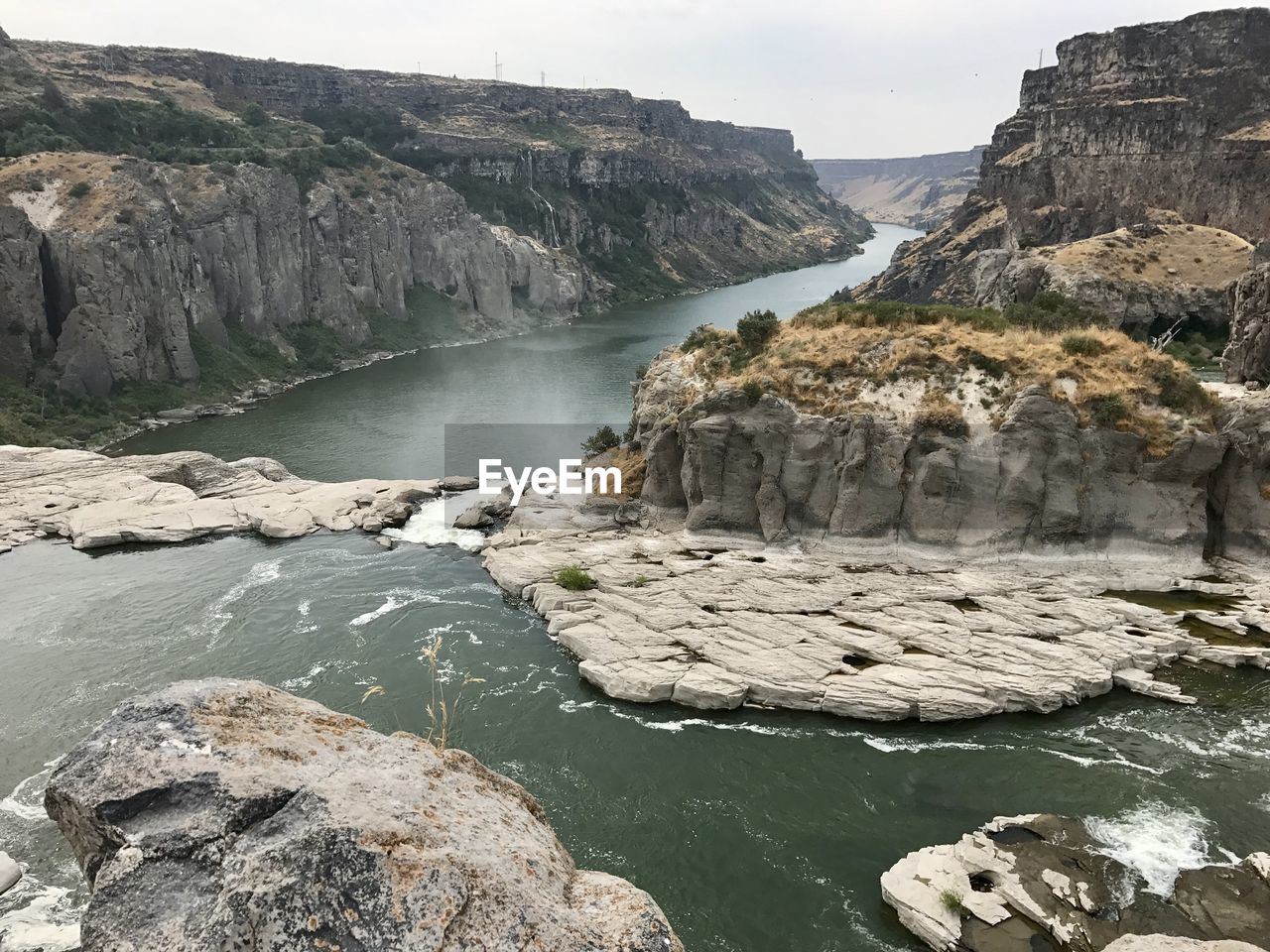 SCENIC VIEW OF WATERFALL BY CLIFF