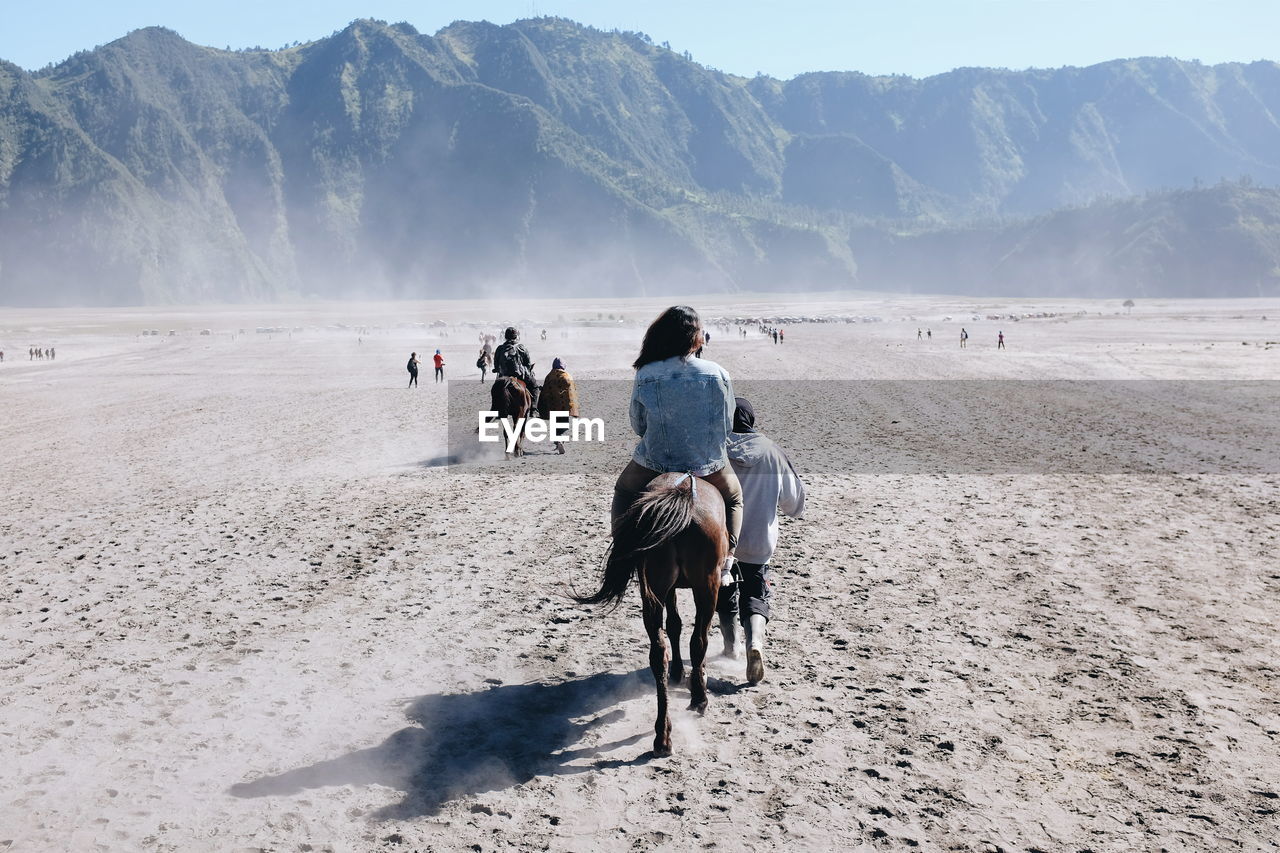 Rear view of people riding horses at bromo-tengger-semeru national park