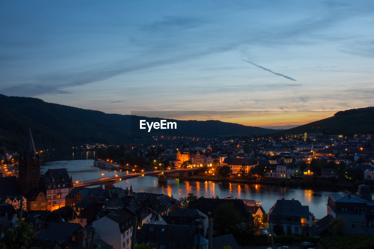 Illuminated cityscape against sky during sunset