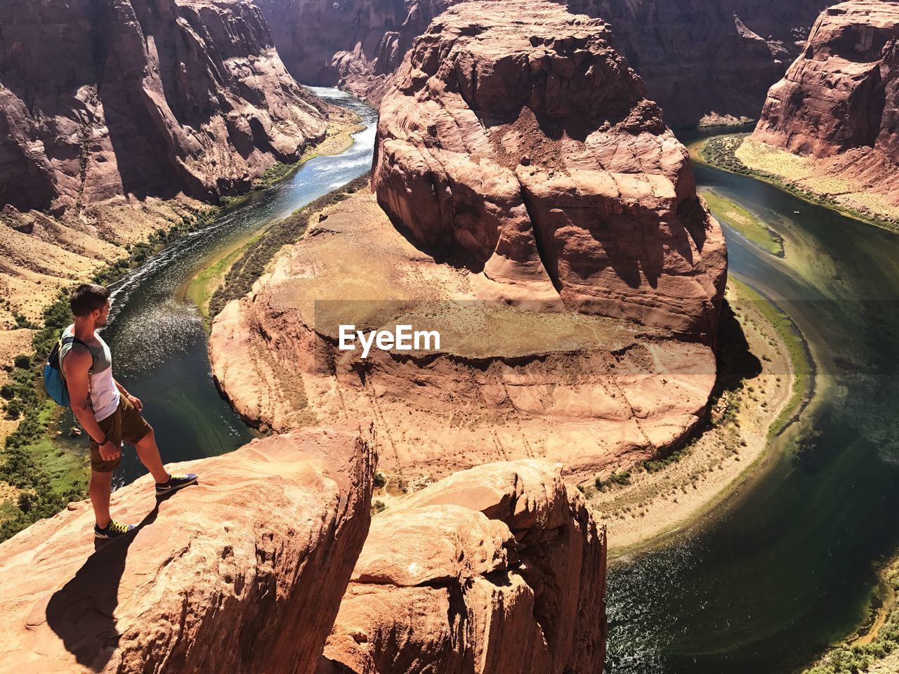 Man standing on rock by river at horseshoe bend