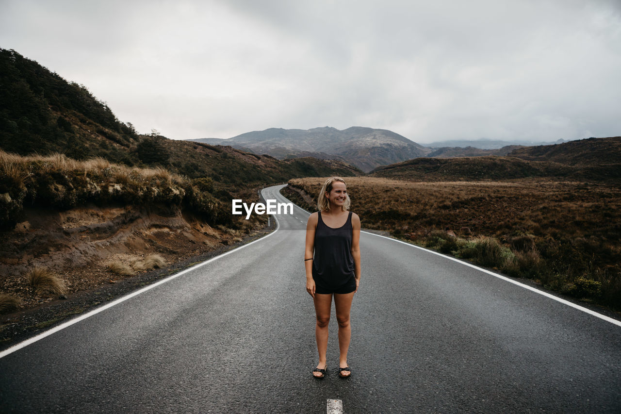 Woman standing on road against sky