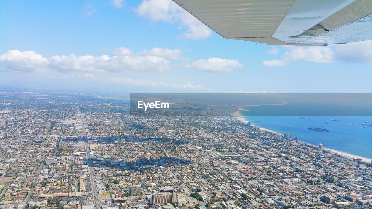 Aerial view of sea and cityscape against sky