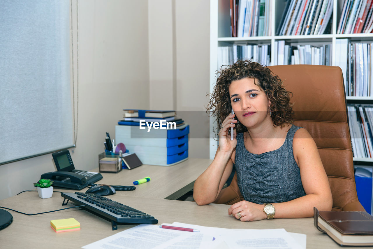 Businesswoman talking on phones while working in office