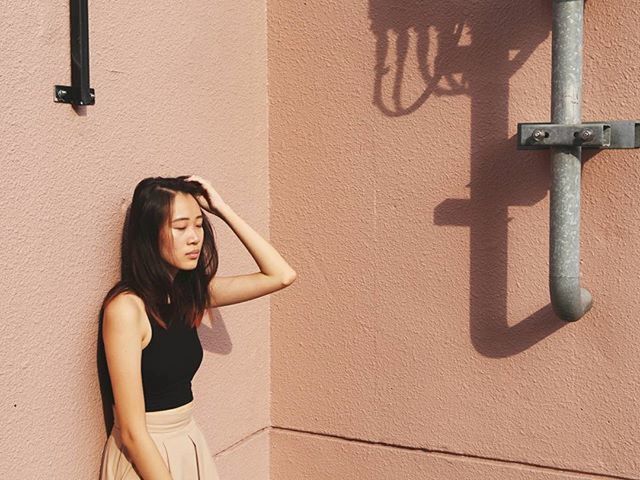 PORTRAIT OF YOUNG WOMAN STANDING ON WALL