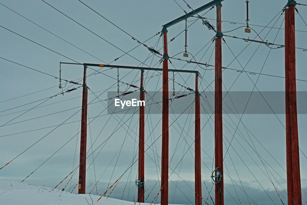 Low angle view of electricity pylons against sky