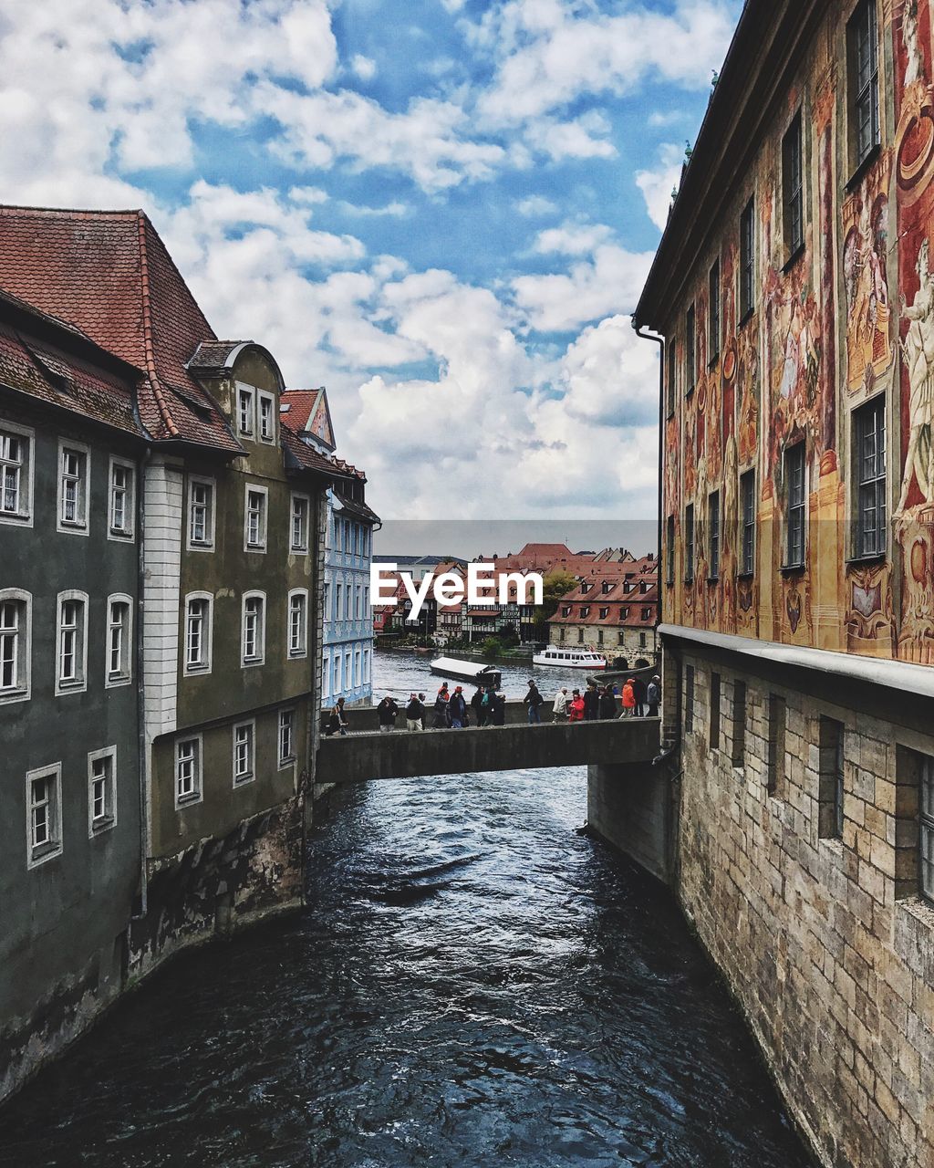 Canal amidst houses against sky in city